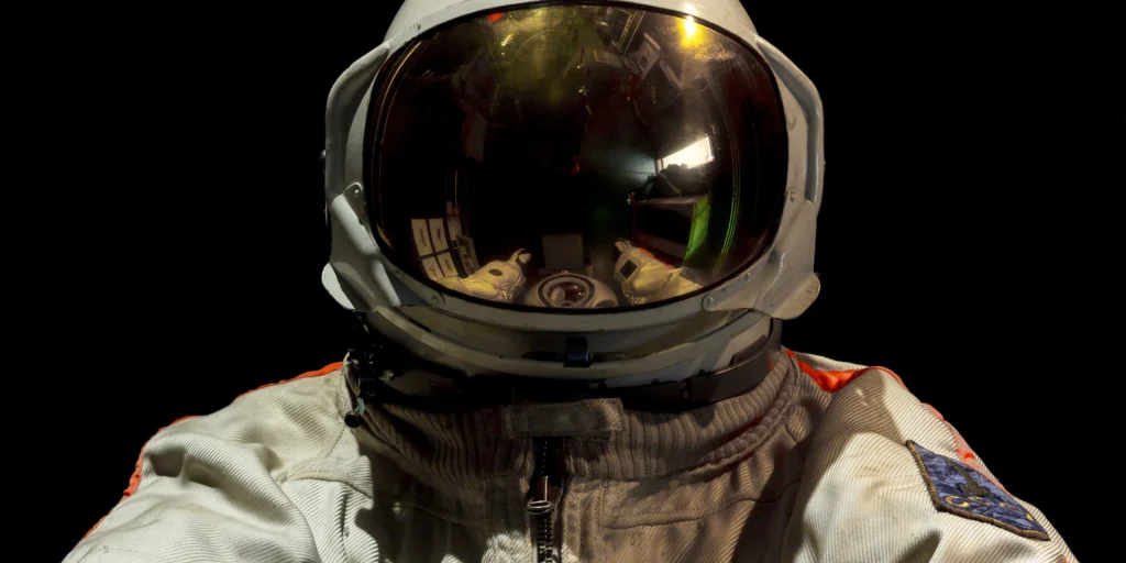 Astronaut looking straight at us from inside a spacecraft module.